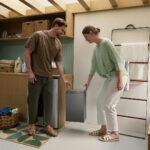 Thumbnail of  Een man en vrouw tillen samen de EcoFlow PowerStream AC 5000 thuisbatterij op in een moderne wasruimte.