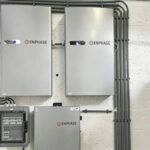 Thumbnail of  Twee Enphase batterijen boven een Enphase IQ System Controller en een groepenkast gemonteerd aan een witte muur.