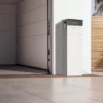 Thumbnail of  Witte Pylontech 15 kWh thuisbatterij met H3X-5K omvormer geïnstalleerd naast een garagedeur bij een oprit.