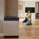 Thumbnail of  Pylontech 15 kWh All-in-one thuisbatterij met H3X-5K omvormer in een moderne woonkamer met een moeder en kind.